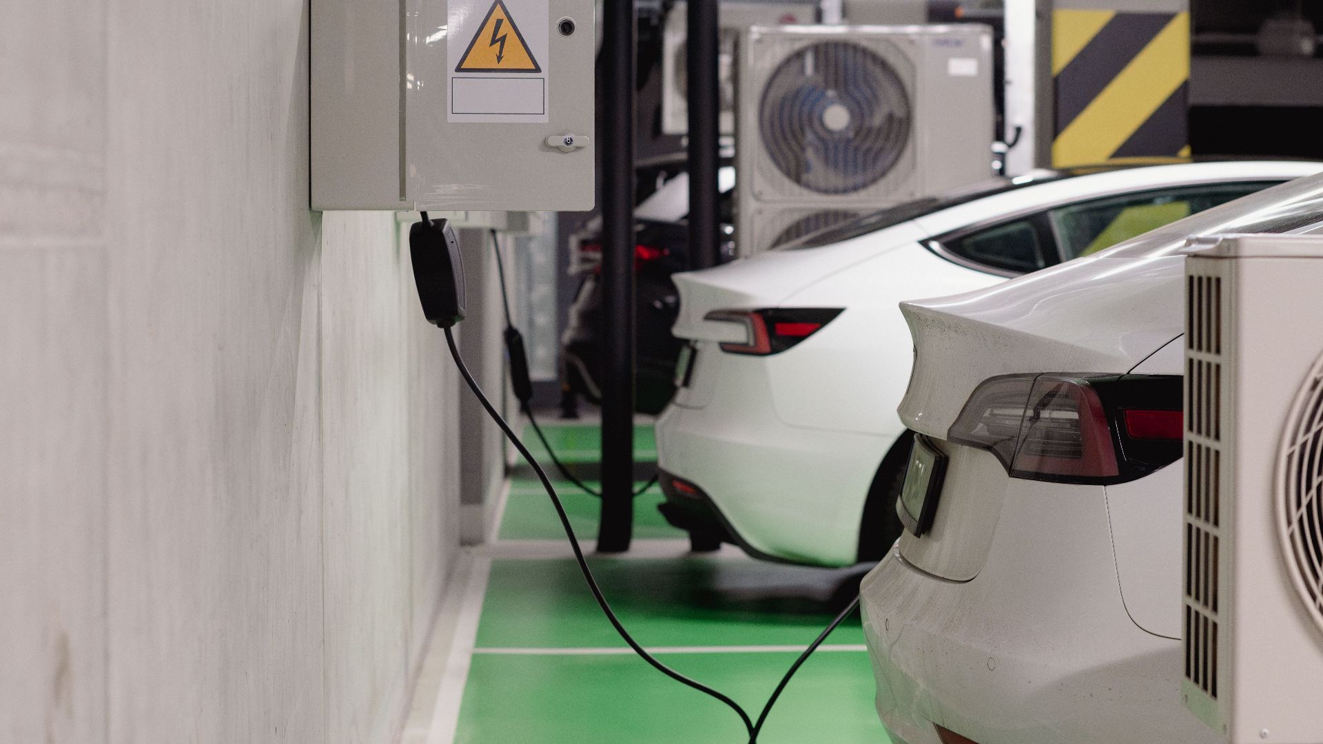 Electric vehicles charging at an indoor station in a modern underground garage.
