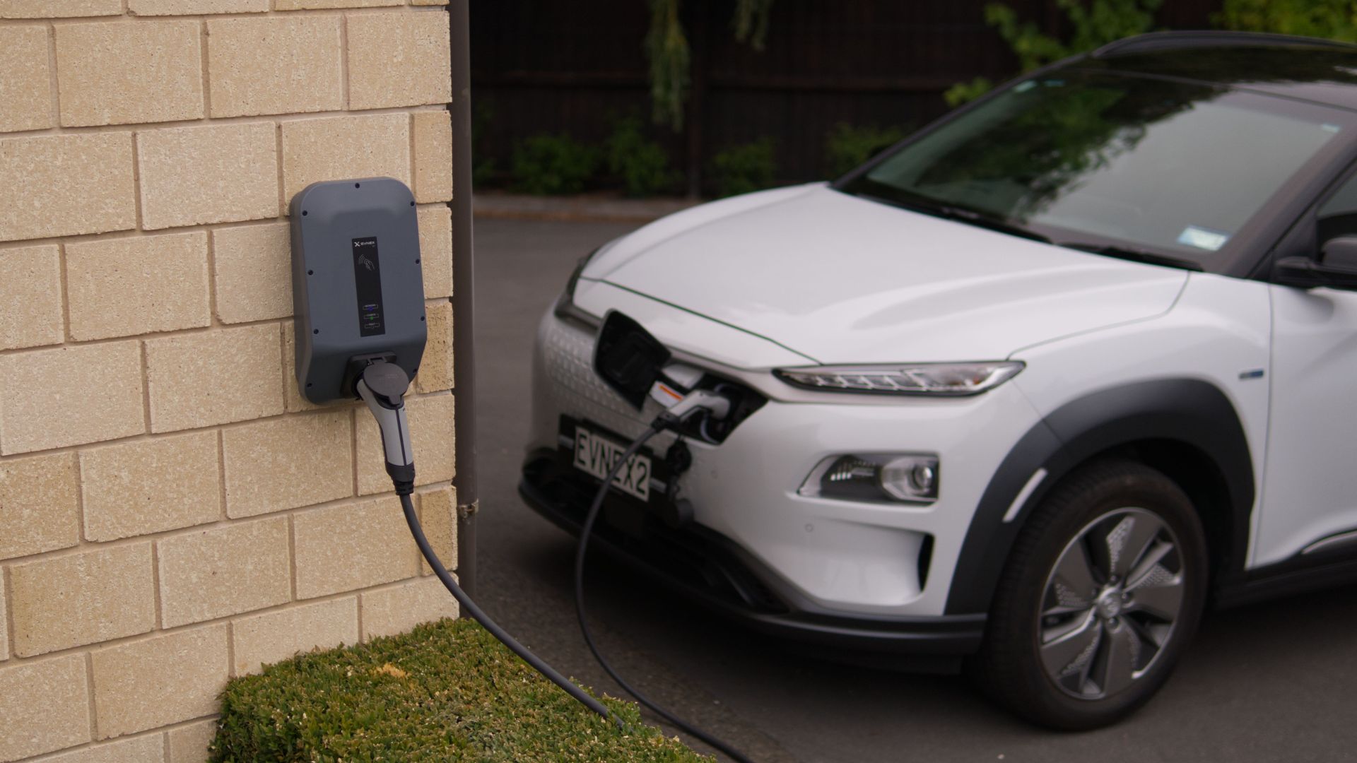 A white electric car charging at a station in Christchurch, New Zealand, showcasing modern eco-friendly transportation.