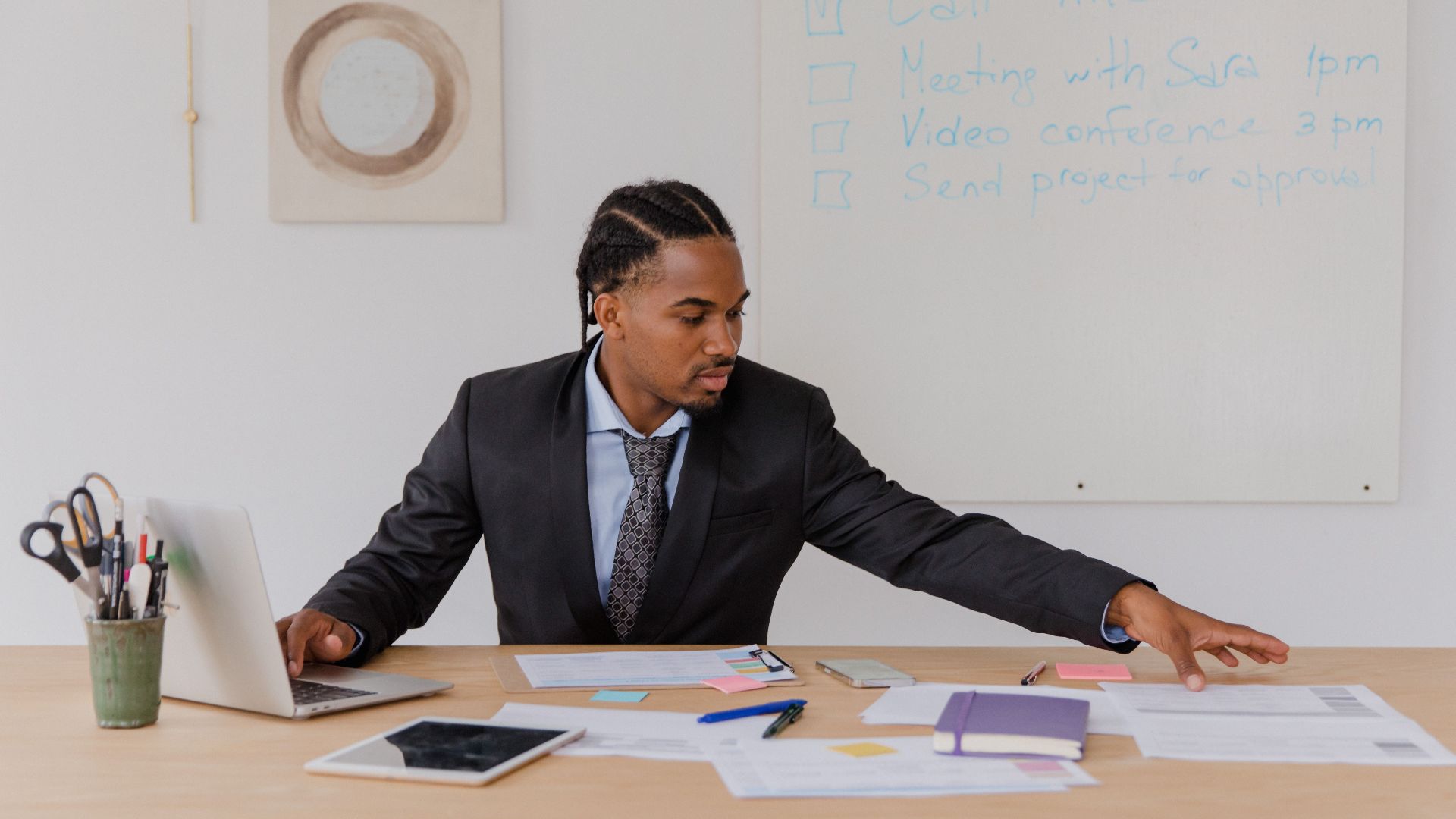 Business professional organizing documents at a desk in a modern office setting.