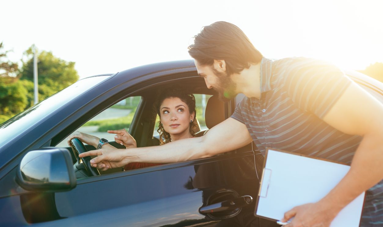 Driving school or test. Beautiful young woman learning how to drive car together with her instructor.