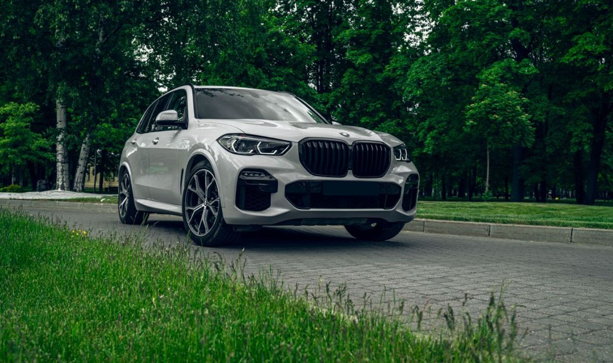 White BMW X5 SUV parked on a scenic road surrounded by lush greenery, showcasing elegance and style