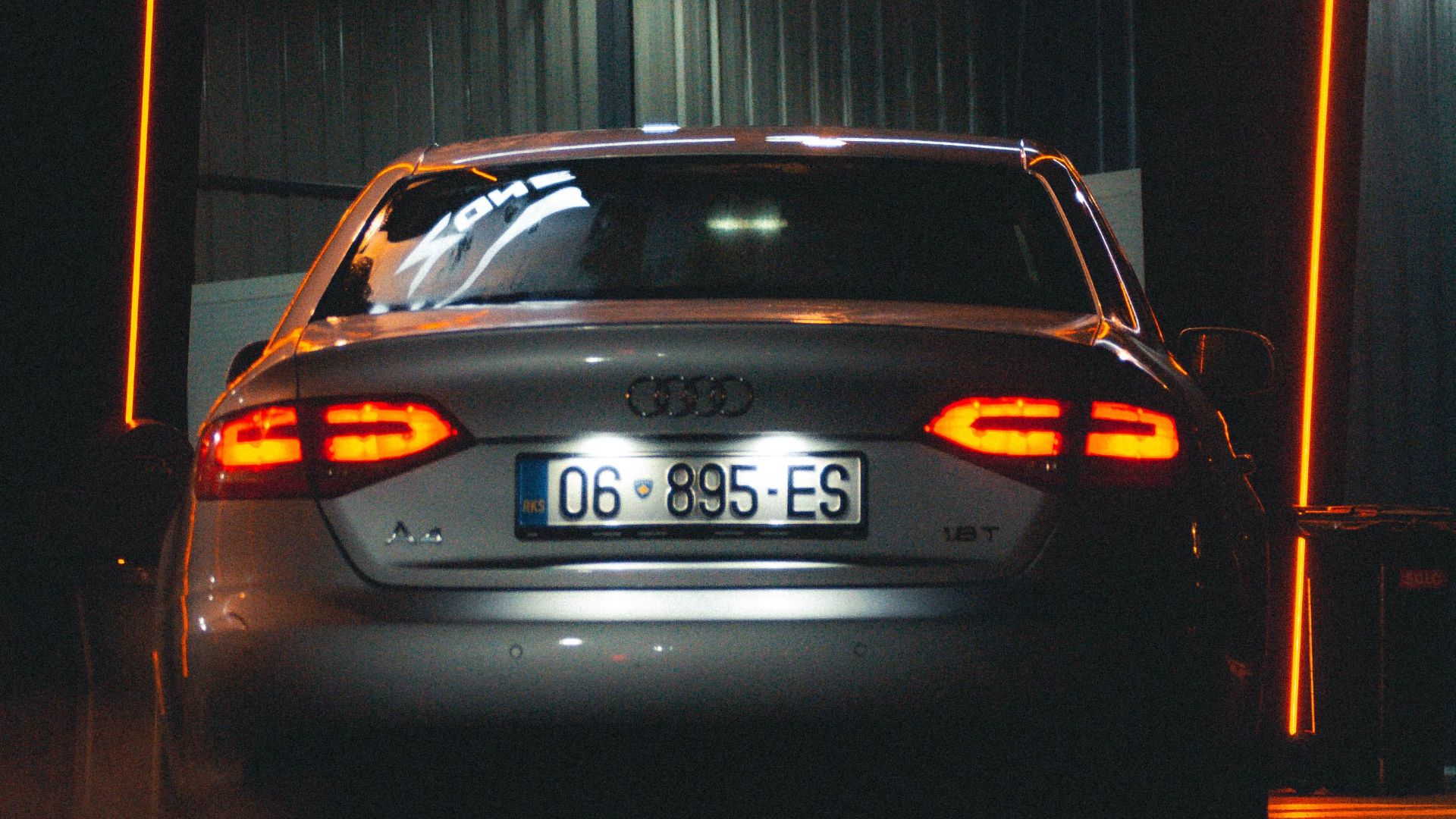 A silver Audi A6 parked in an underground garage with ambient lighting and visible license plate.
