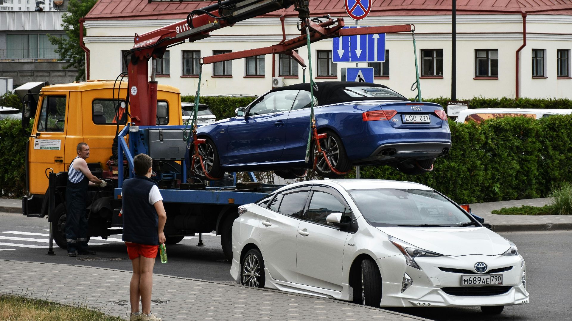 Towing a blue Audi convertible in a bustling city street.