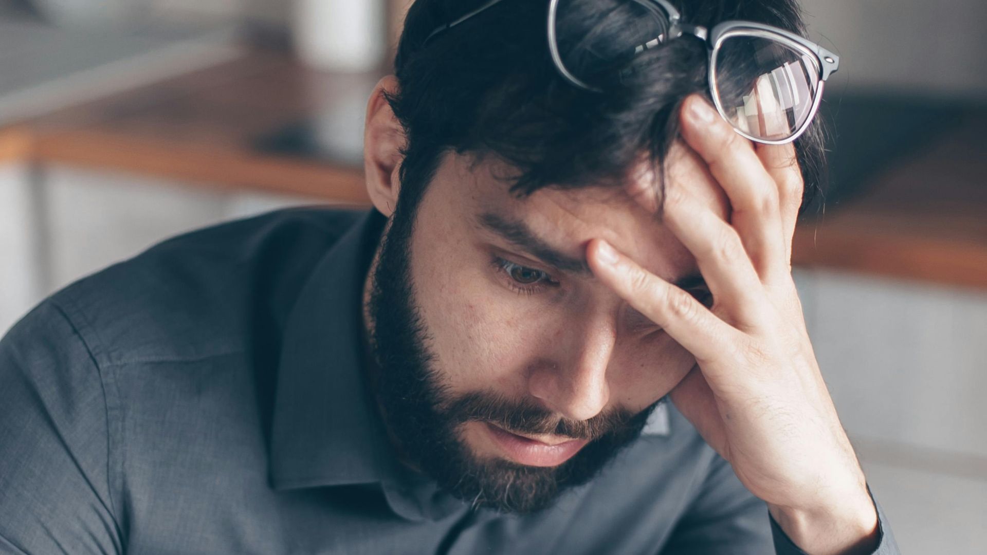 Man with eyeglasses on head looks worried as he reads paperwork, expressing concern.