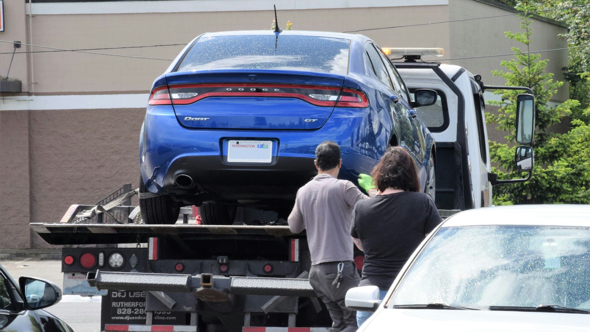 a blue car being loaded onto a flatbed truck