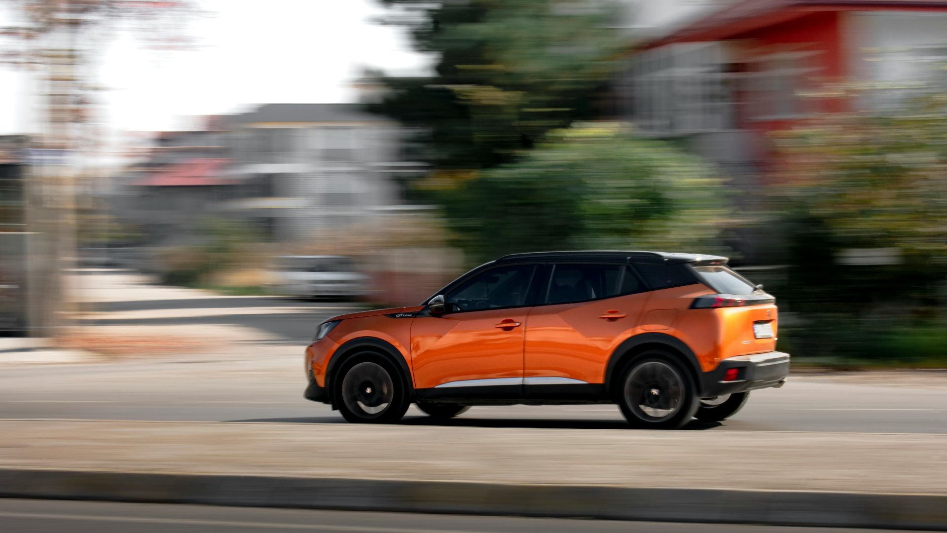 Orange SUV driving fast on an urban road, showcasing motion blur and speed.