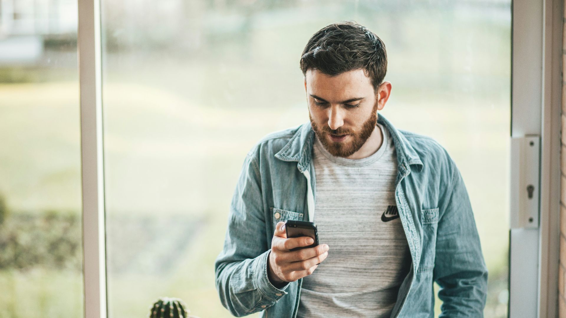man holding a smartphone near the window