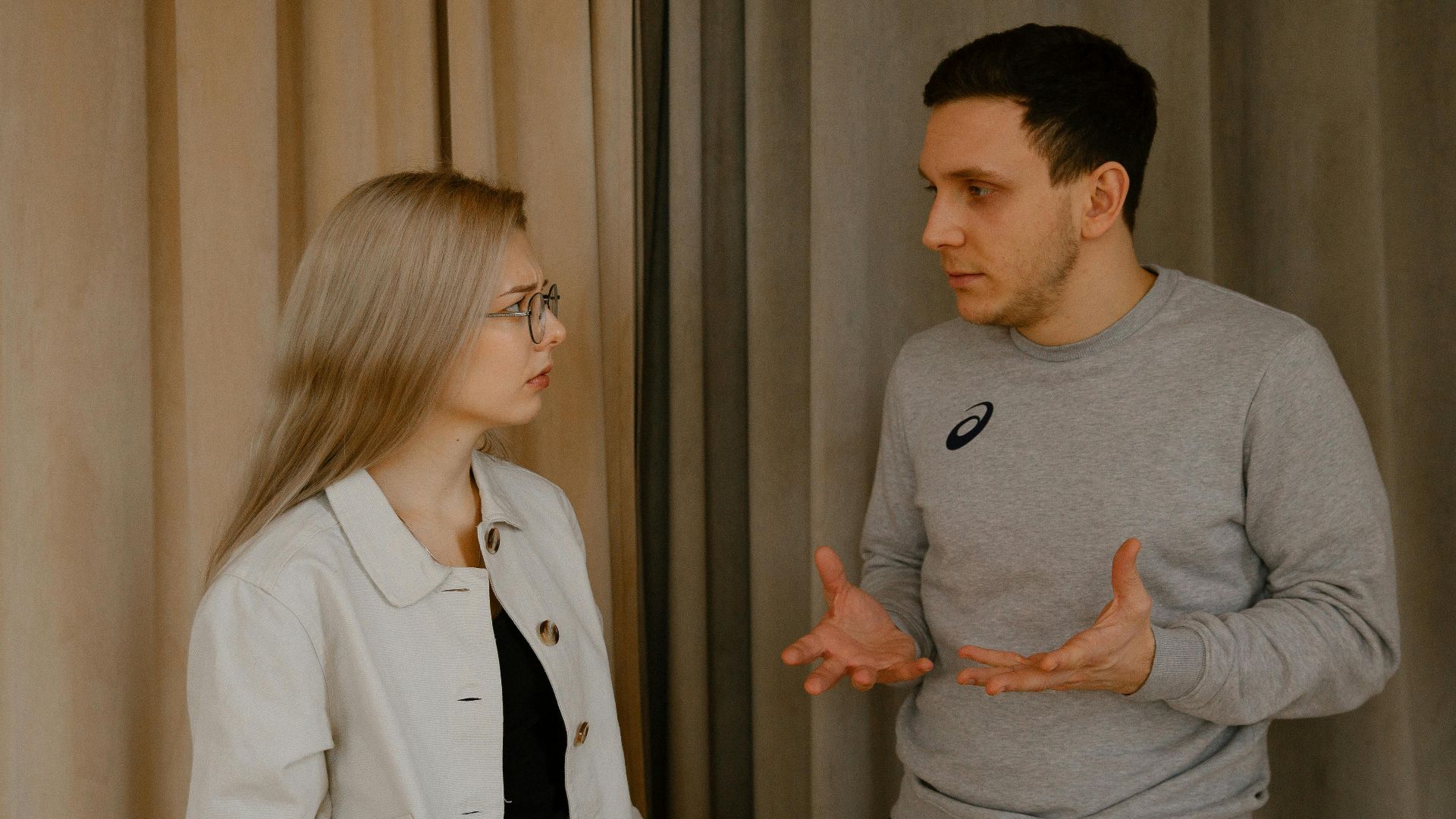 A young couple passionately discussing indoors, capturing intense emotions and gestures.