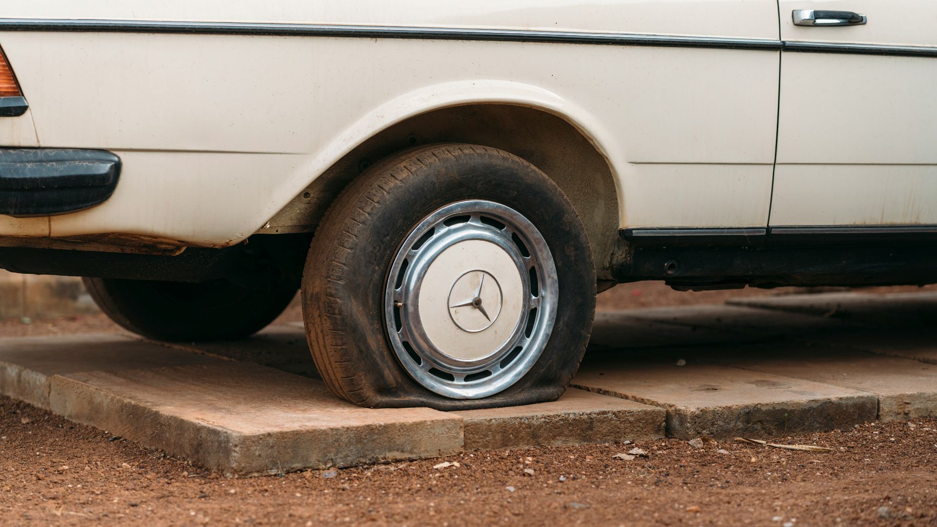 A flat tire on an old white car.