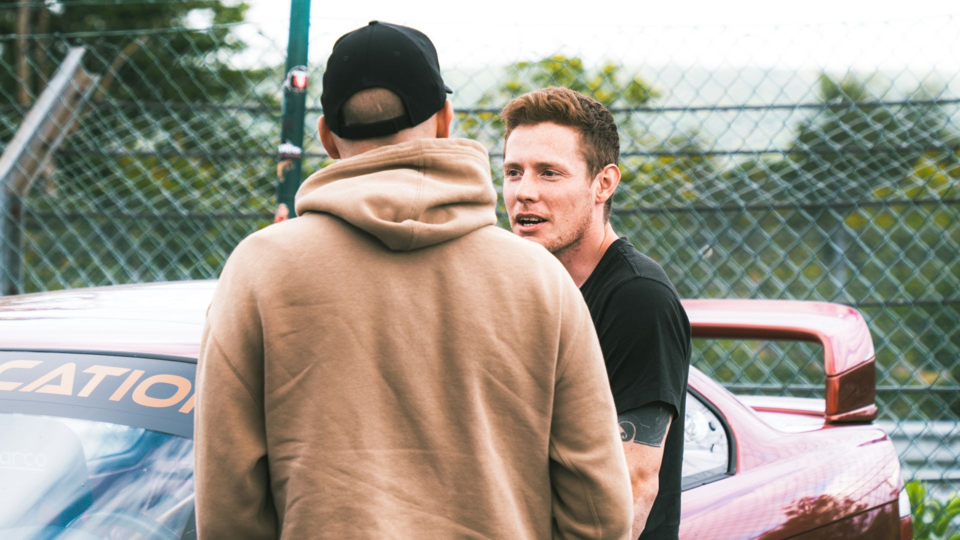 A group of men standing next to each other in front of a car