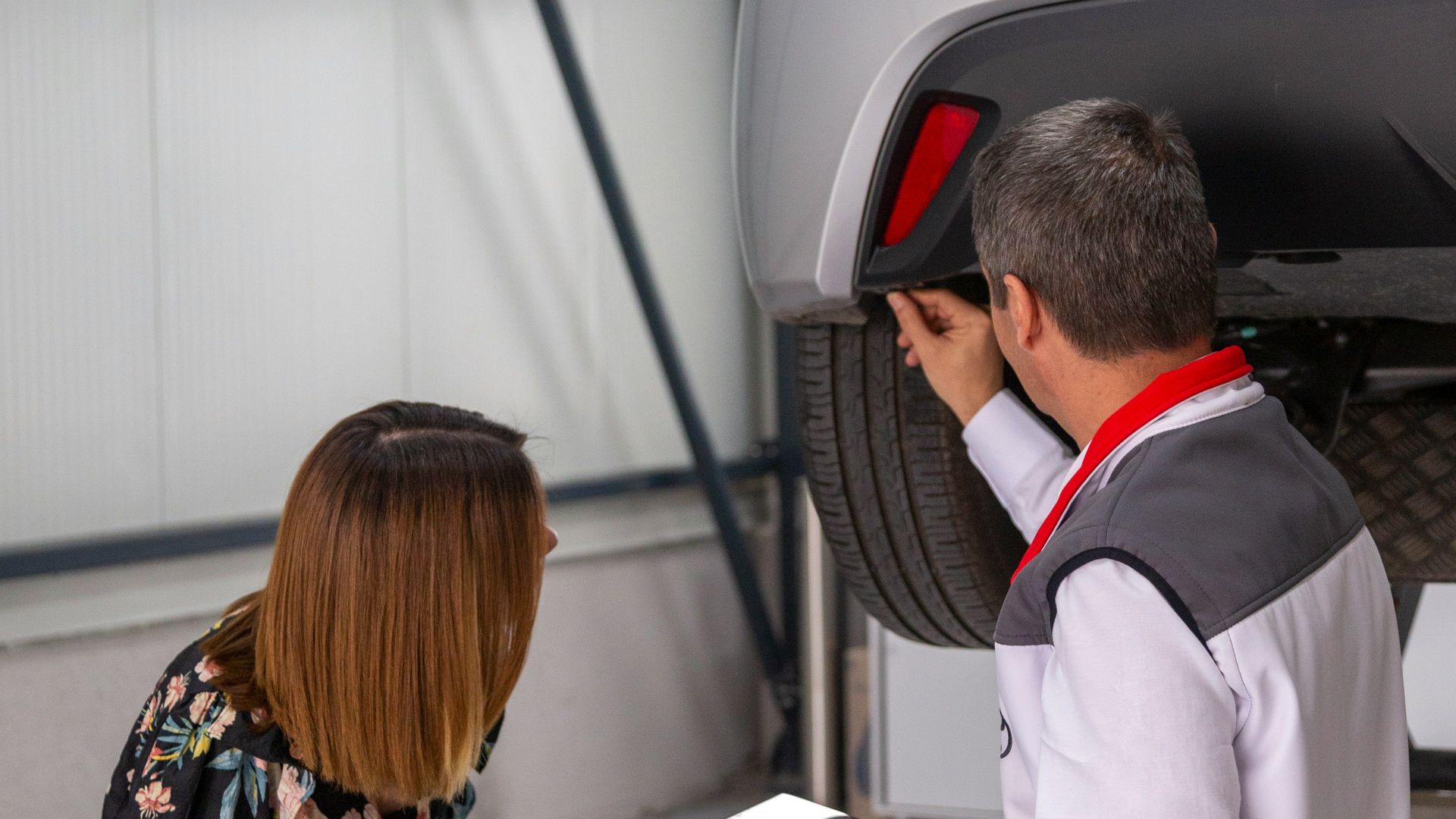 A man and a woman looking under a car