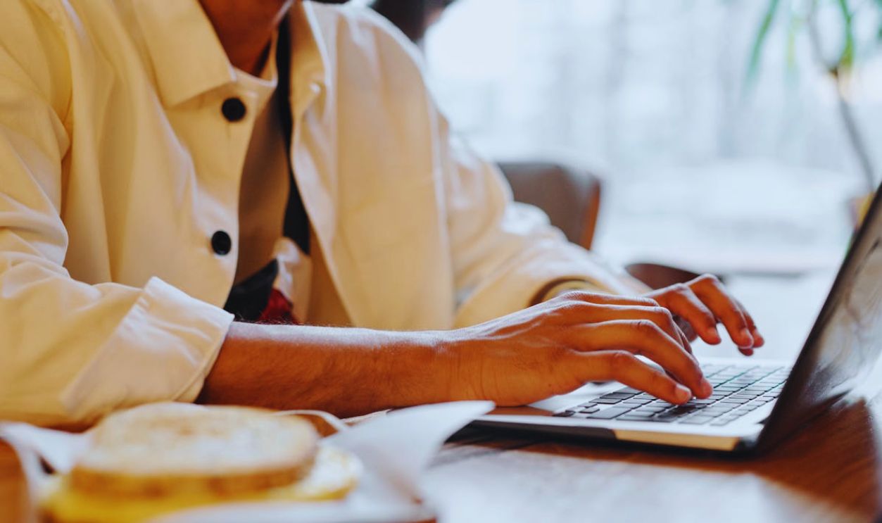 Close-up of hands typing on a laptop keyboard in a warm indoor environment with soft lighting