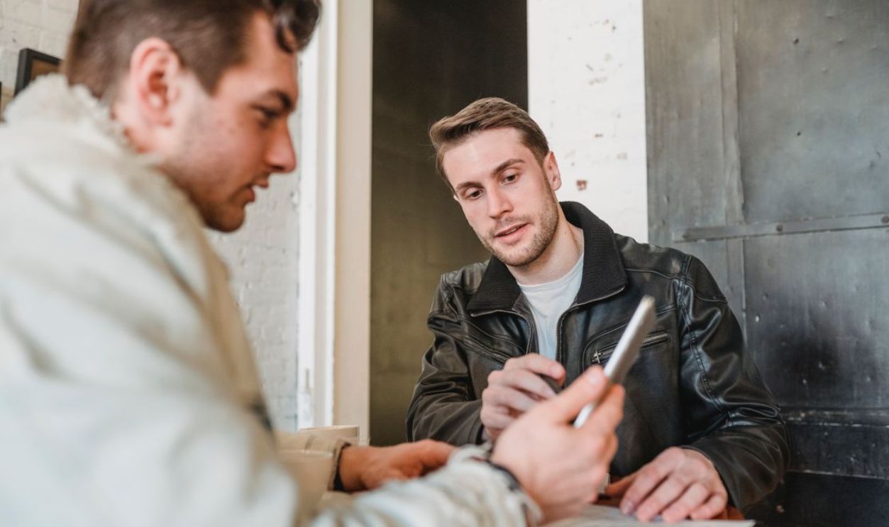 Two men engaged in a business discussion at a cafe, using a tablet and paper notes