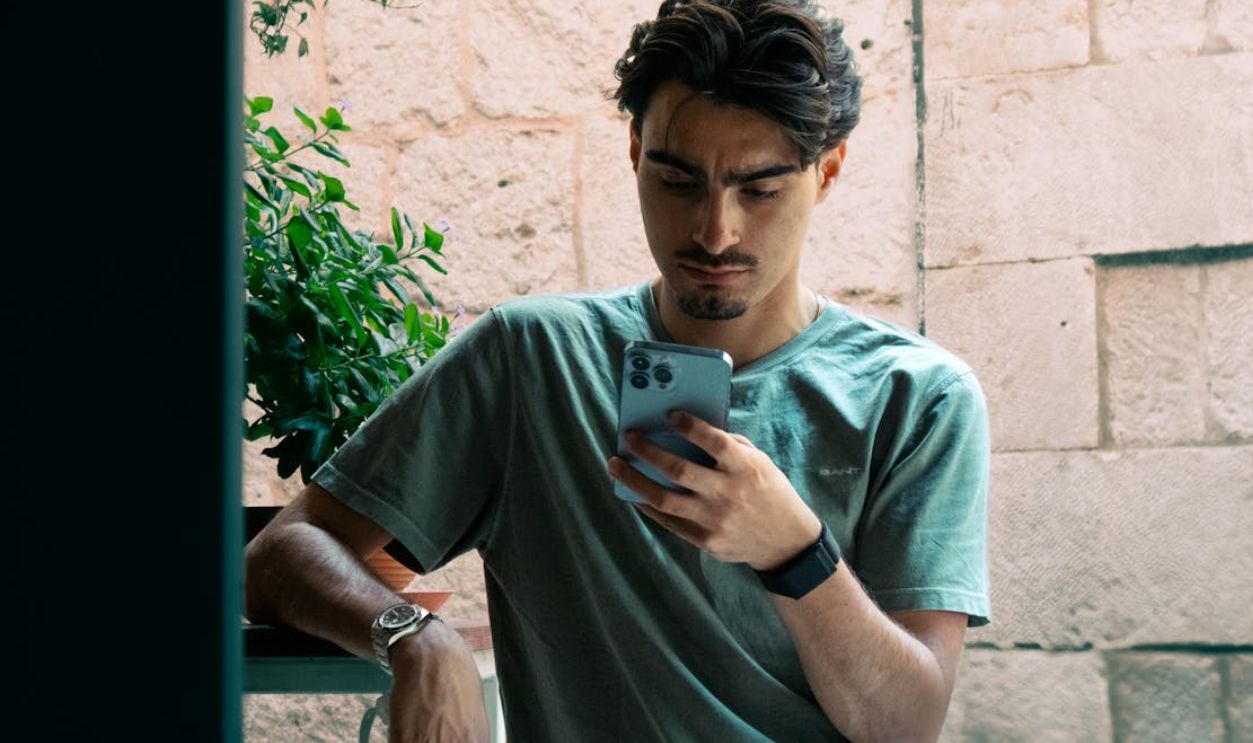 A young man in casual attire checking his phone outside in Split, Croatia