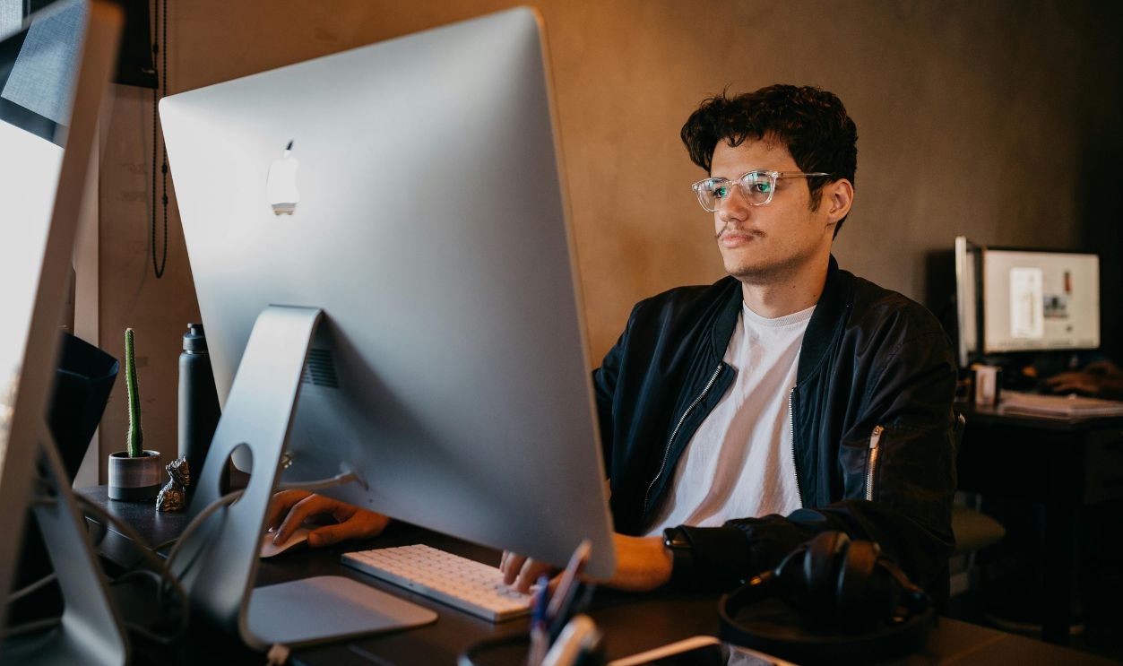Man focused on work at a desktop computer in an office environment with modern decor