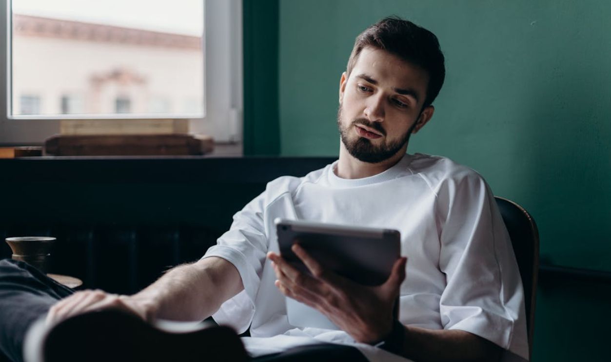 Pensive man using a tablet while relaxing at home. Modern lifestyle concept
