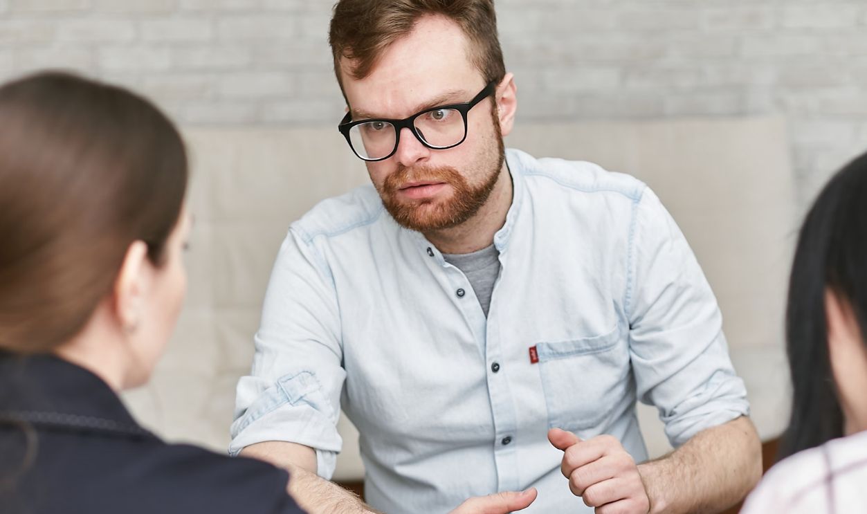 Group of adults engaged in a focused work meeting indoors, discussing plans.