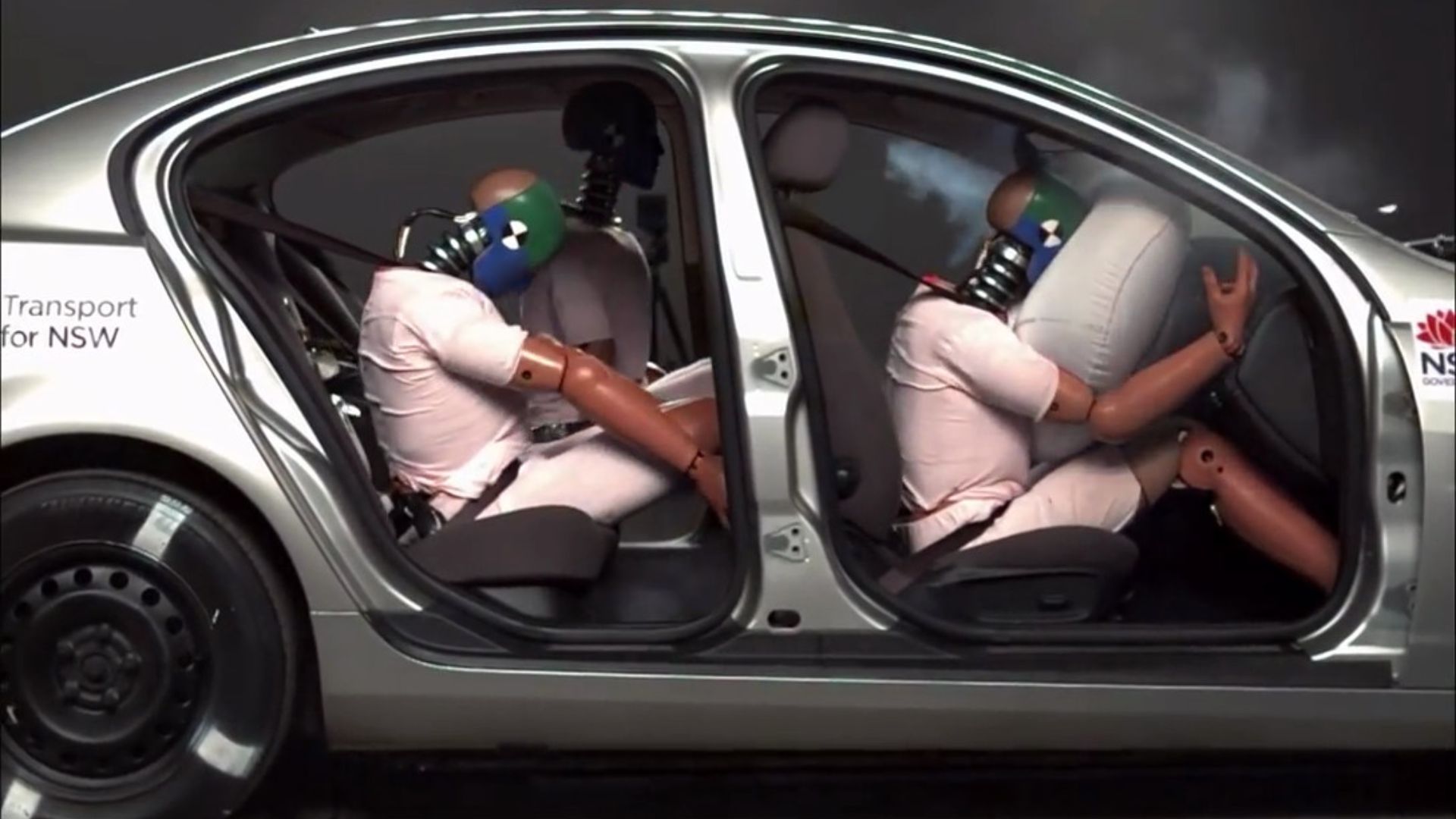 car crash test at 40km/h with crash test dummies with different safety measures: safety belt and airbag (front),  safety belt only (back, right) and no safety measure (back, left).