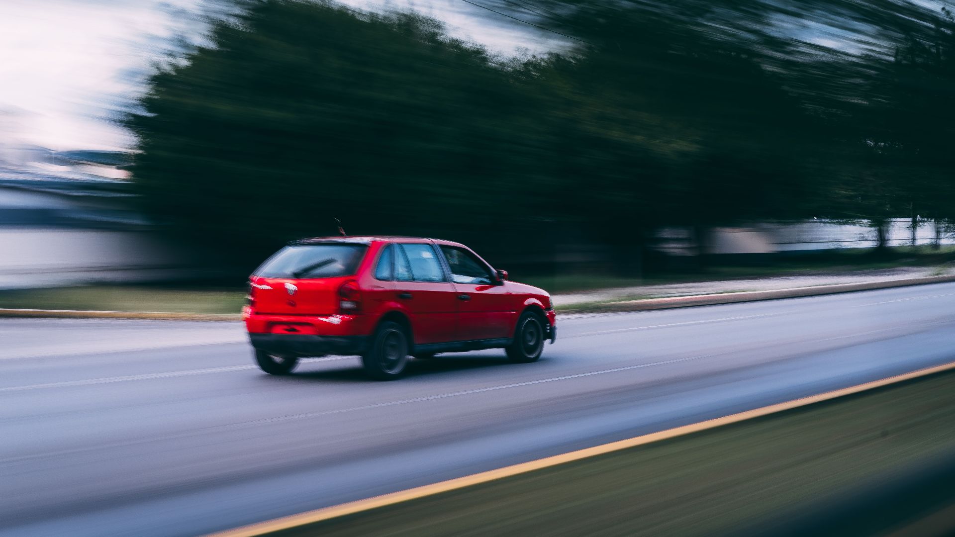 A red car speeding on a city road captured with motion blur, showcasing dynamic motion.