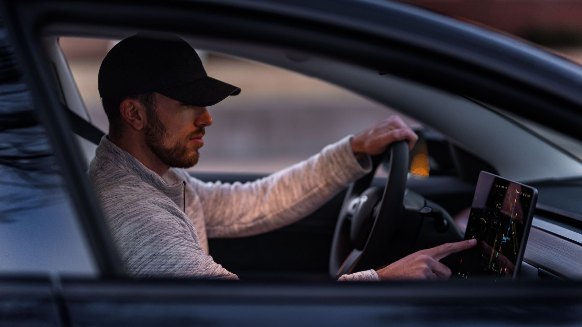 A man interacts with a touchscreen inside an electric car, driving through Dallas, TX.