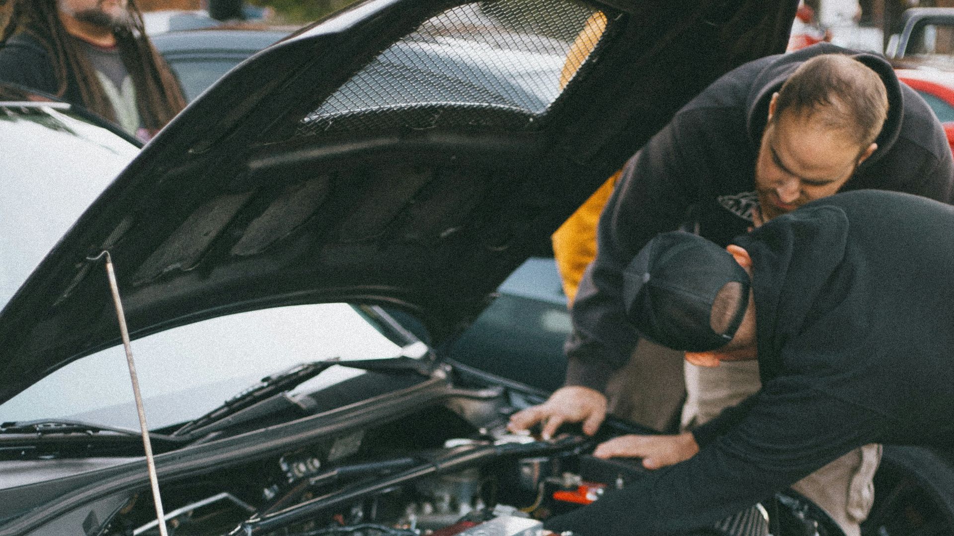 man in black jacket standing beside black car