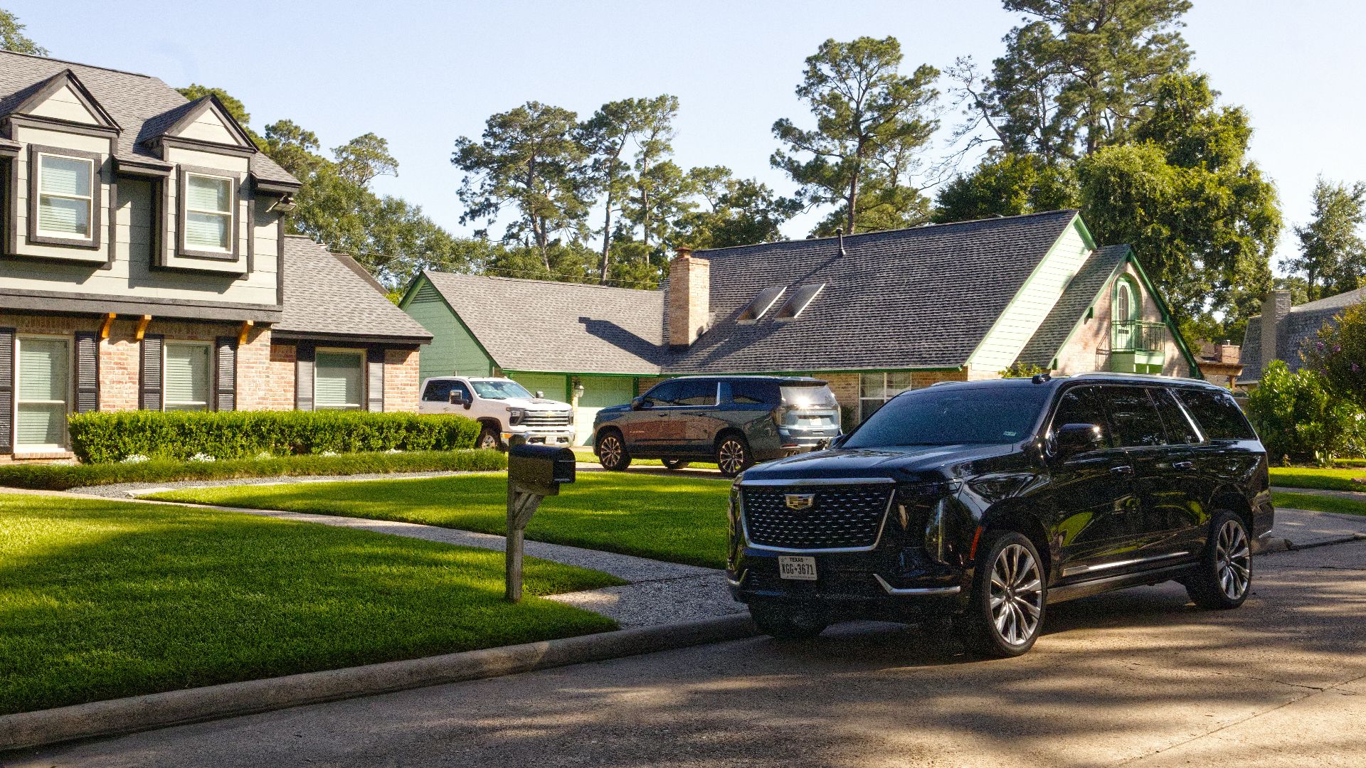 Black suv parked on a sunny suburban street with houses.