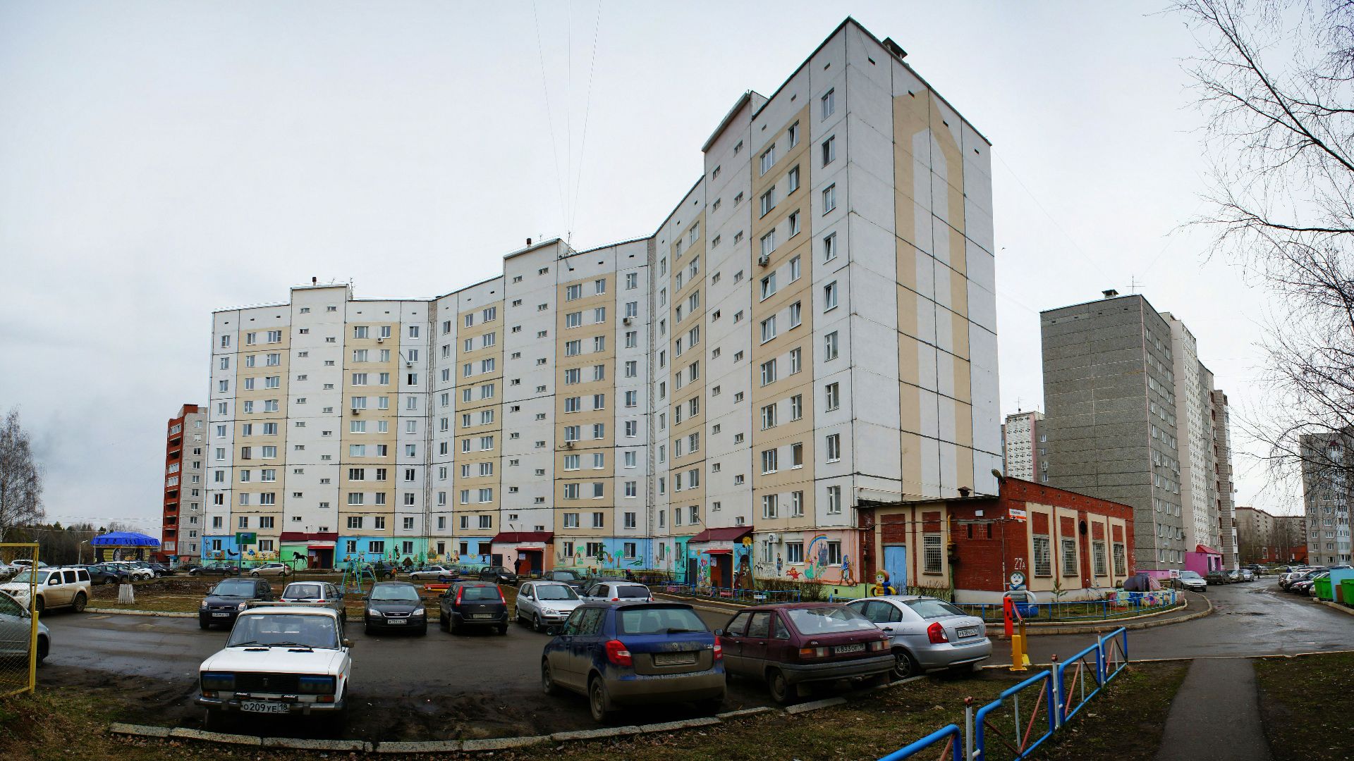 Apartment buildings with cars parked in front.