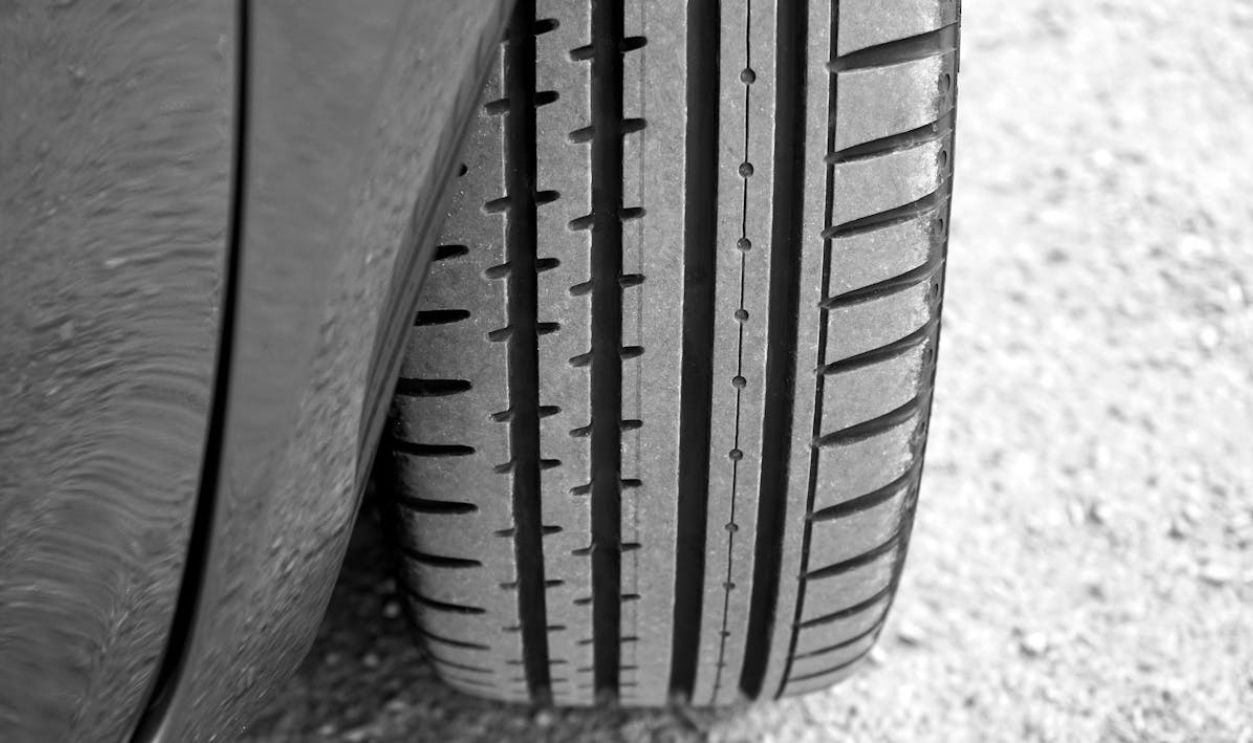 Detailed view of vehicle tire on a gravel surface, showcasing tread pattern.