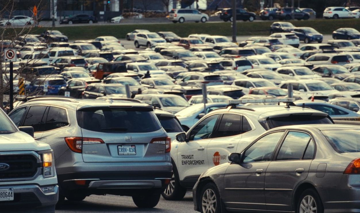 Vast and crowded car park in an urban setting during daytime, featuring various vehicles.