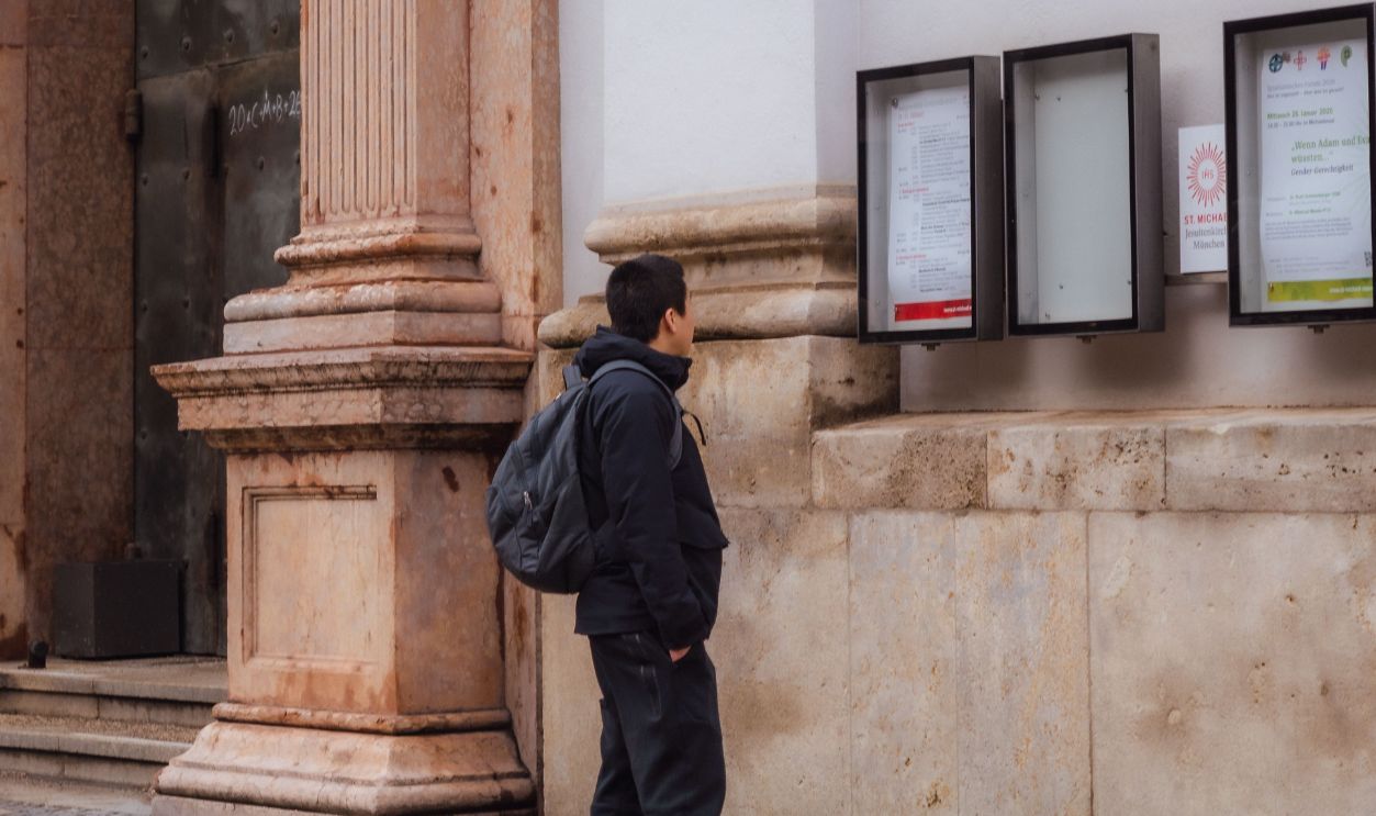 A man reads a notice board outside a historic church in Munich, Germany.