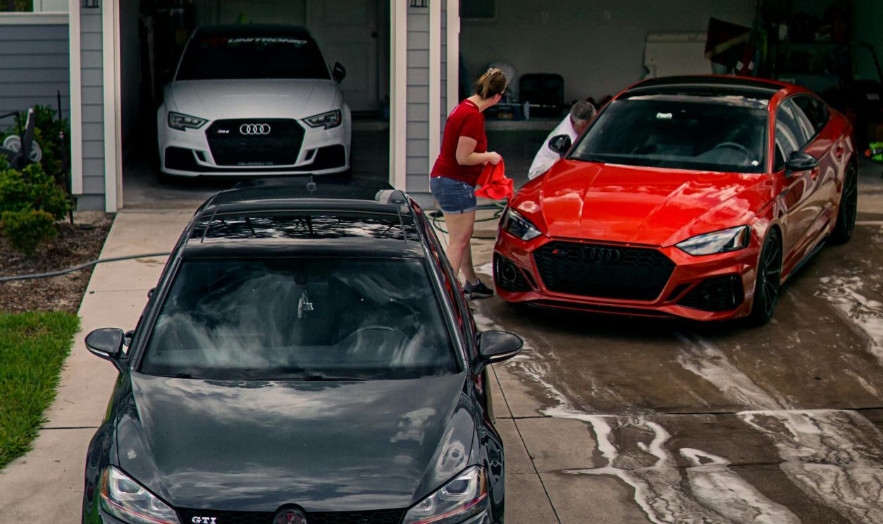 A person washing modern cars in a driveway