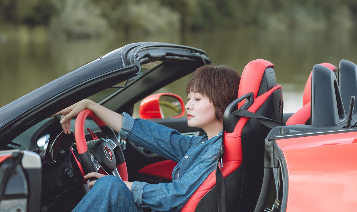 Stylish woman in denim lounging in a red convertible car outdoors