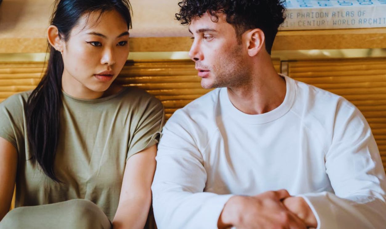 Asian woman and man sitting together having a serious conversation. Indoor setting
