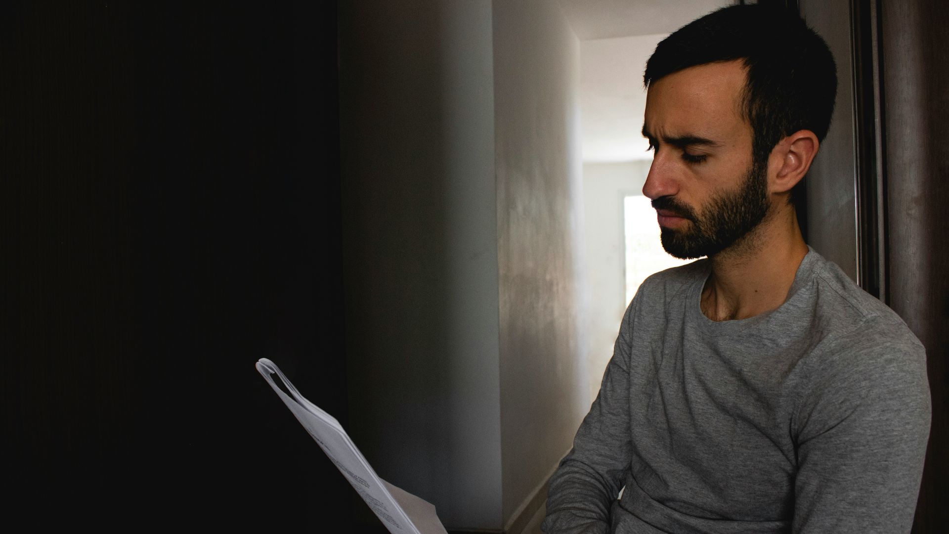 man in gray crew neck shirt holding white printer paper