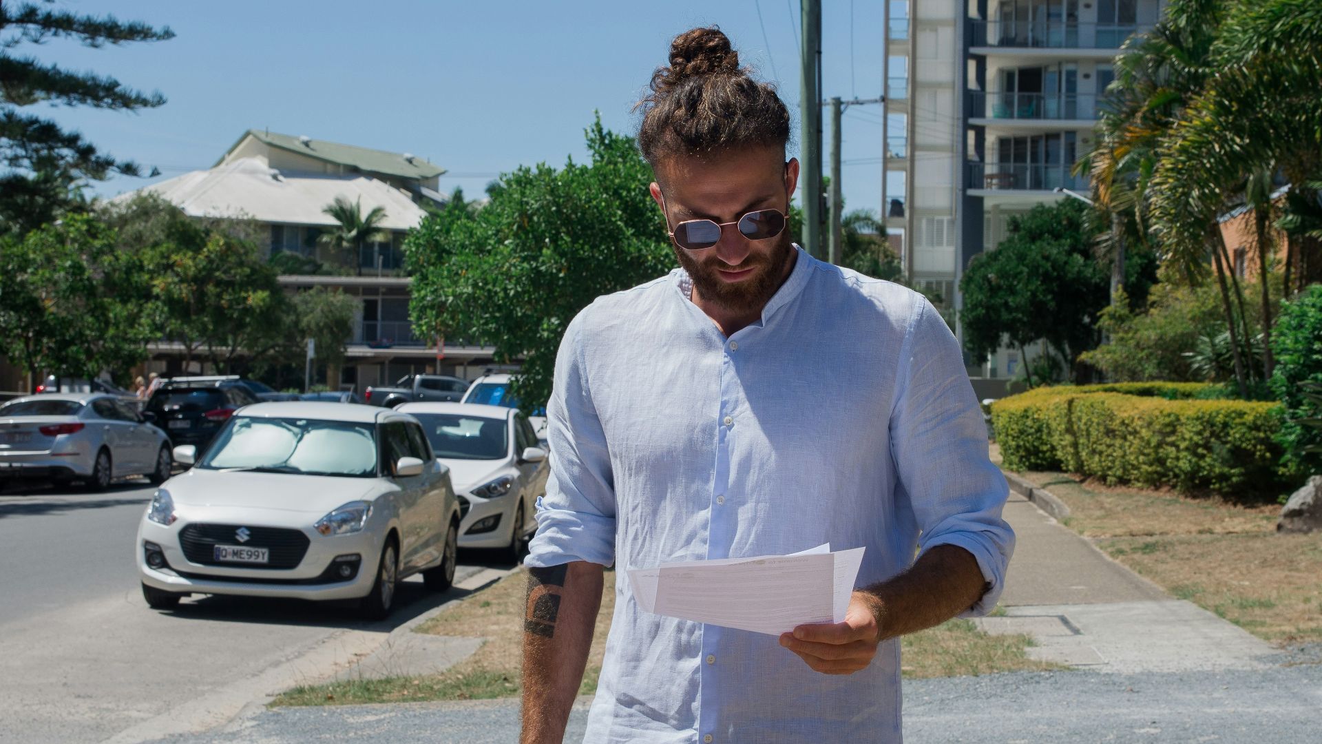 man in white button up t-shirt holding white printer paper
