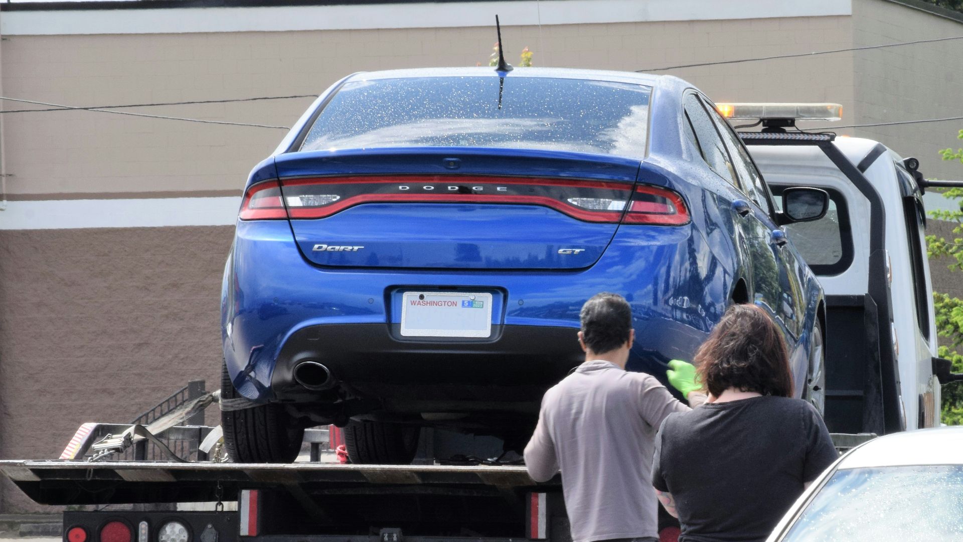 a blue car being loaded onto a flatbed truck