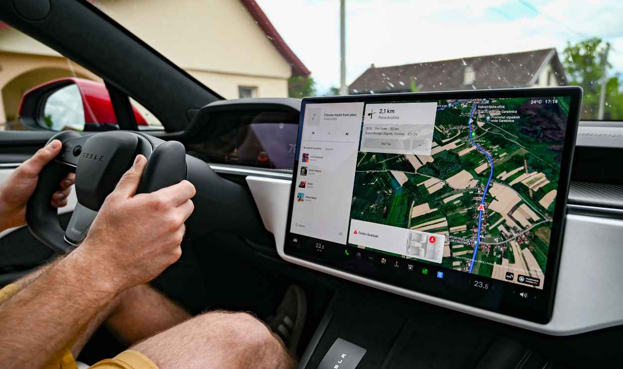 Man driving Tesla using GPS on touchscreen dashboard