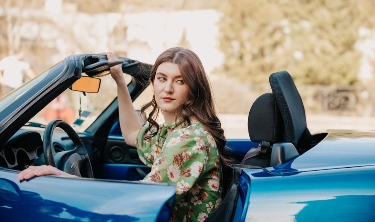 Stylish woman enjoying a drive in a blue convertible on a sunny day