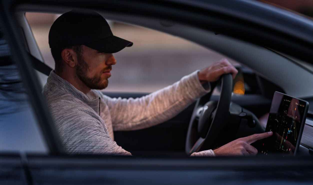 A man interacts with a touchscreen inside an electric car
