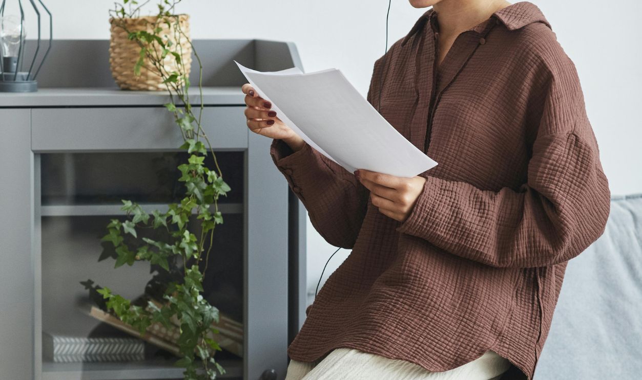 Focused woman with headset reviewing document in comfortable home setting