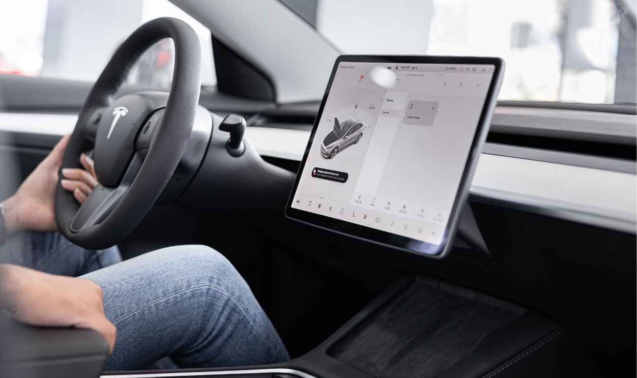 Interior of an electric car showing steering wheel and large touchscreen display