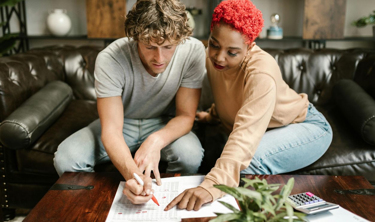 A man and woman collaborating on a project at home, focusing on paperwork