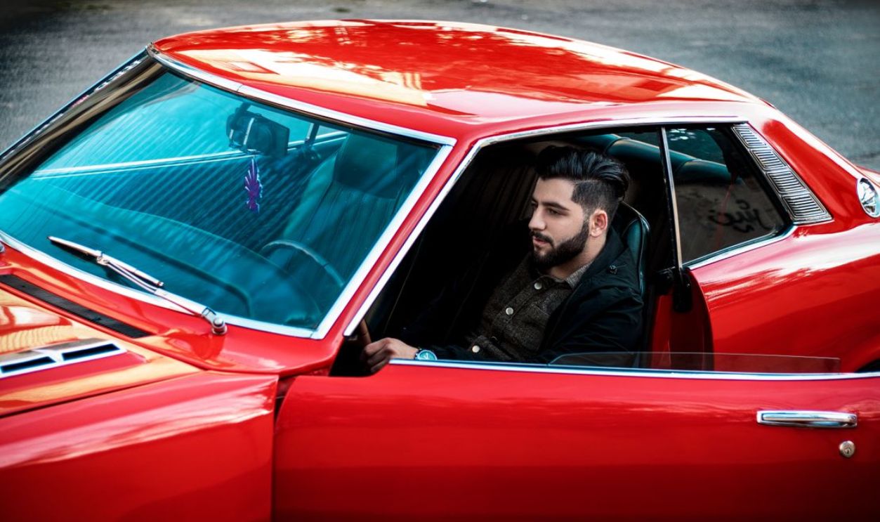 Bearded man in a vintage red sports car, parked on the street, Rasht, Iran