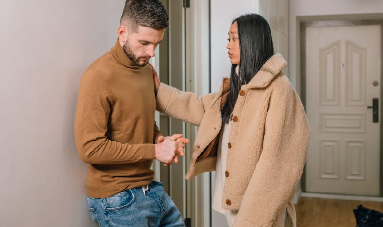An interracial couple engaged in a serious conversation inside a home, showcasing emotion and connection