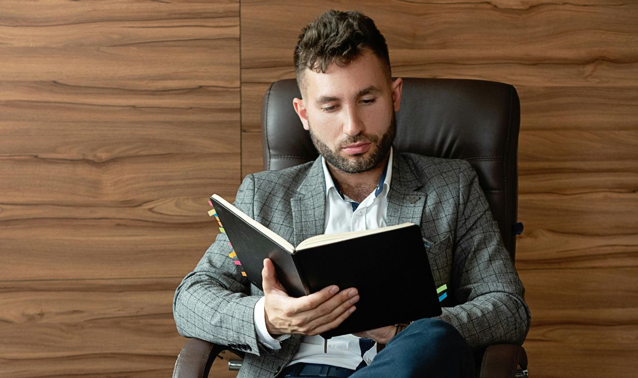 Adult man reading a book while sitting on an office chair