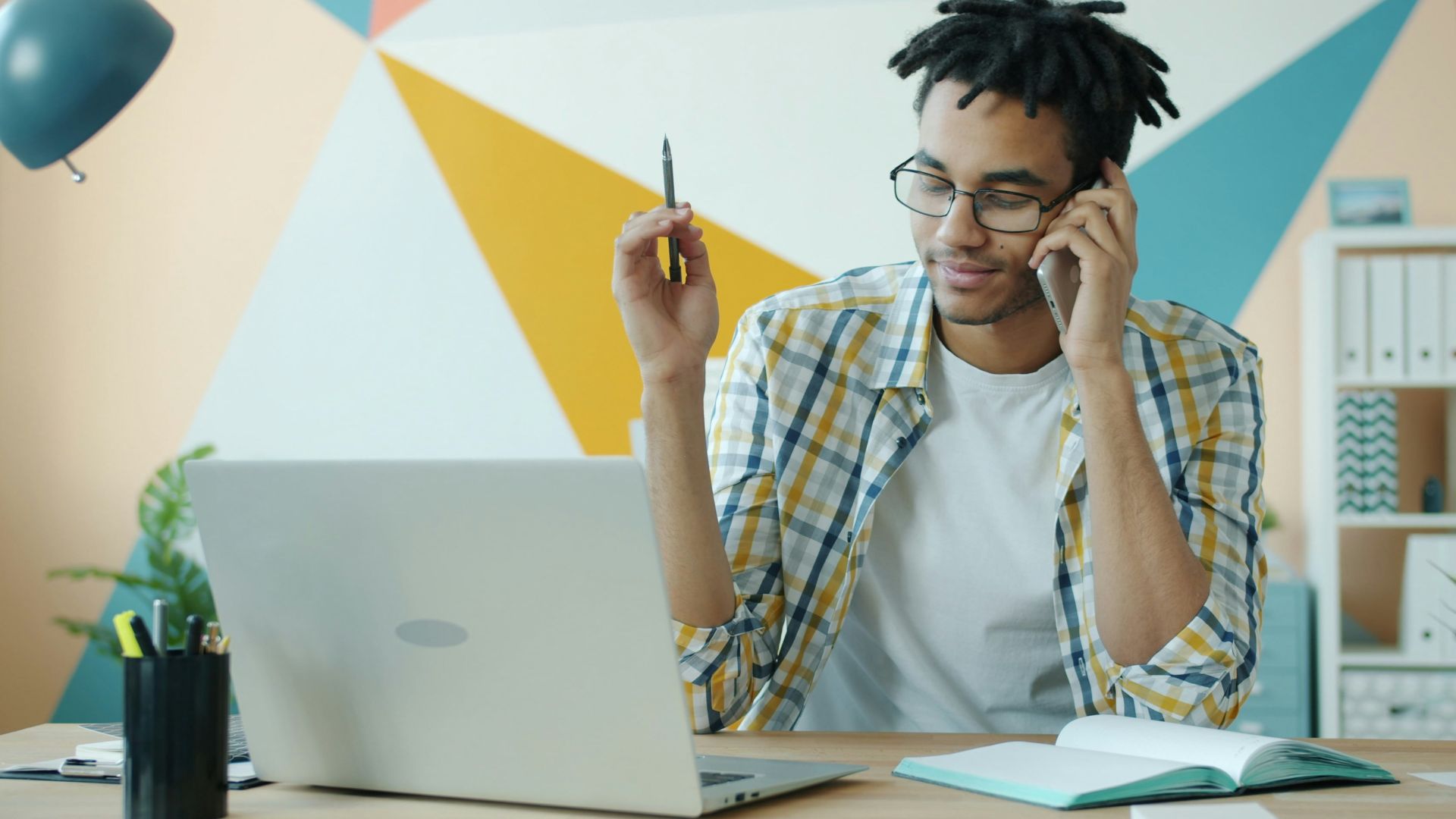 Man talking on phone at desk with laptop.