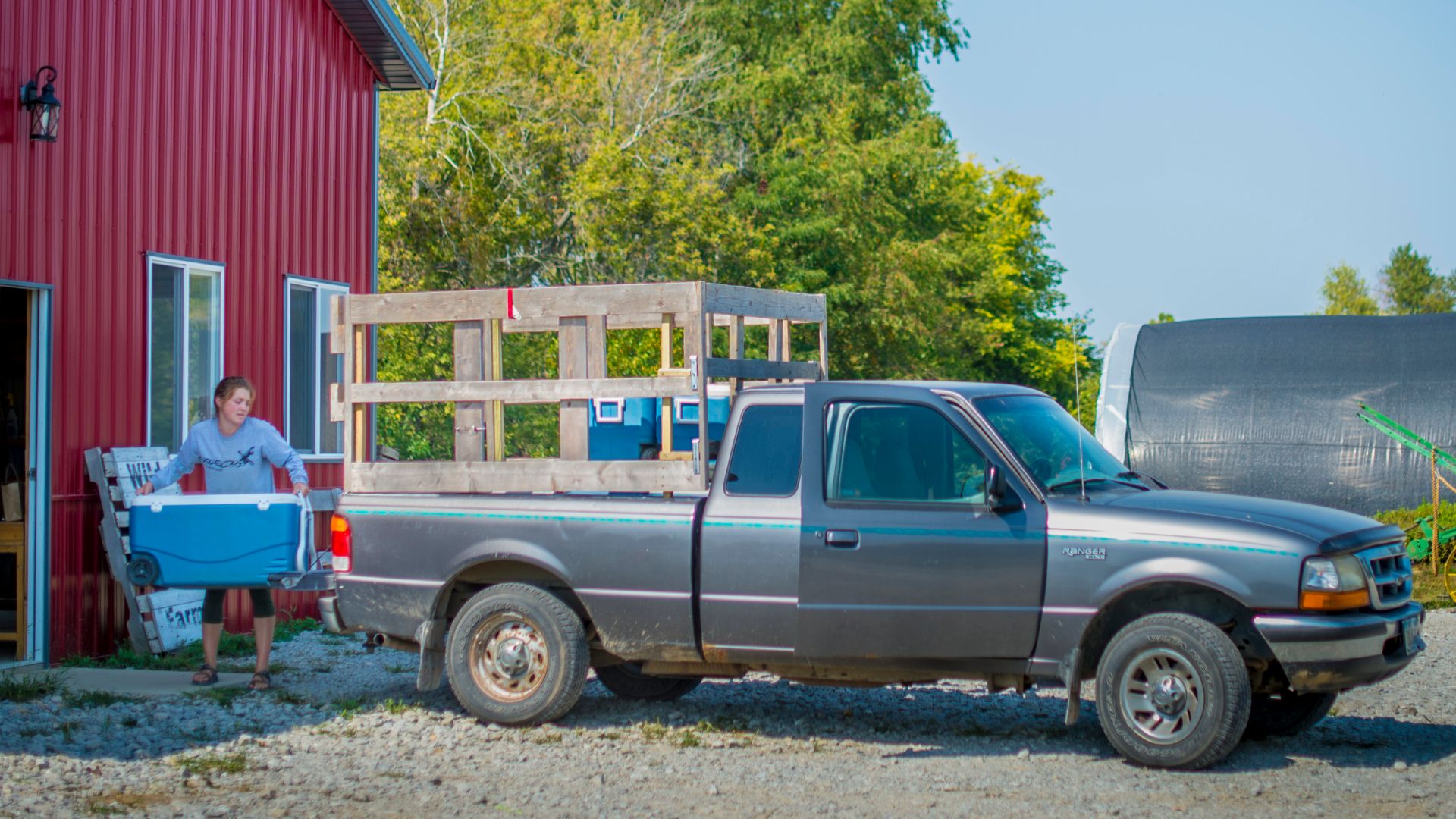 Chloe Matthews loads coolers of vegetables in the truck to help Kate Edwards runs her vegetable Community Supported Agriculture (CSA) that feeds 200 families in her community. Members are able to pick up their weekly share at one of her seven drop sites.
