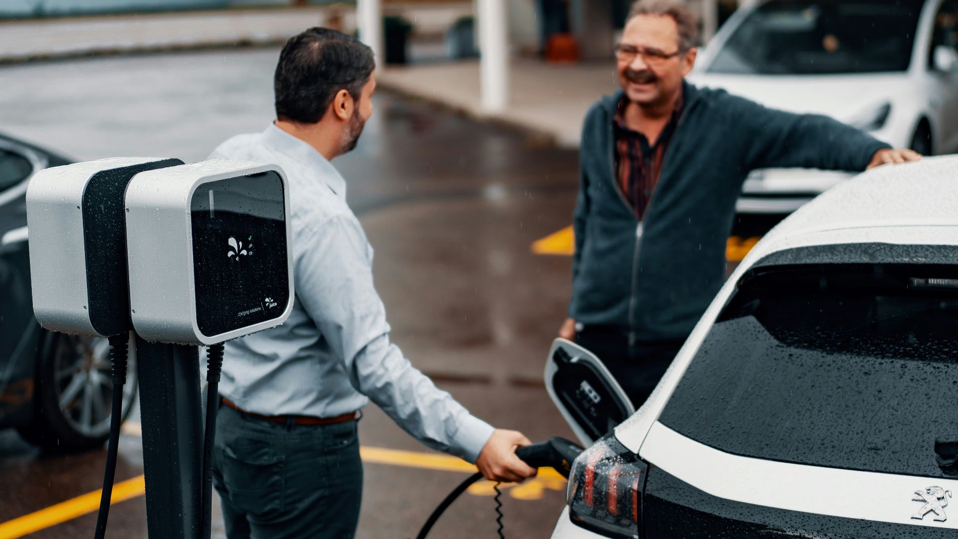 a couple of men standing next to a white car