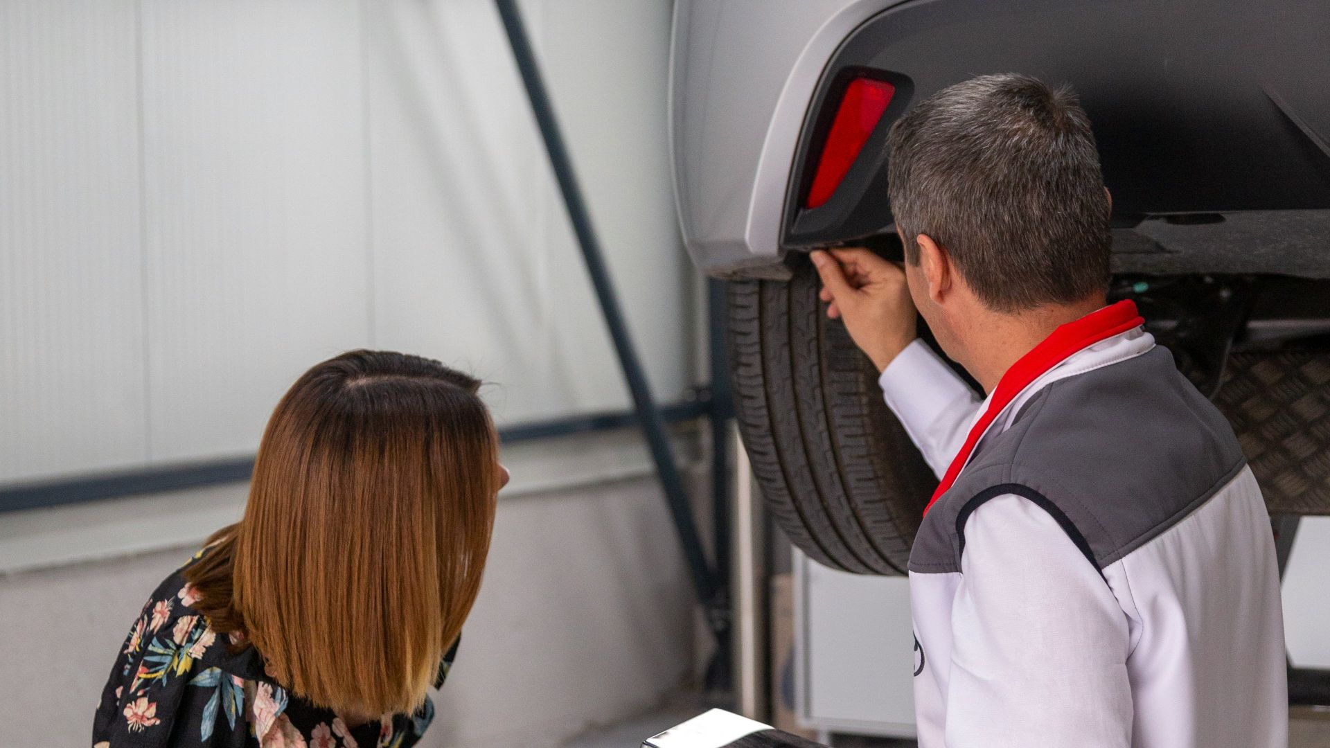 A man and a woman looking under a car