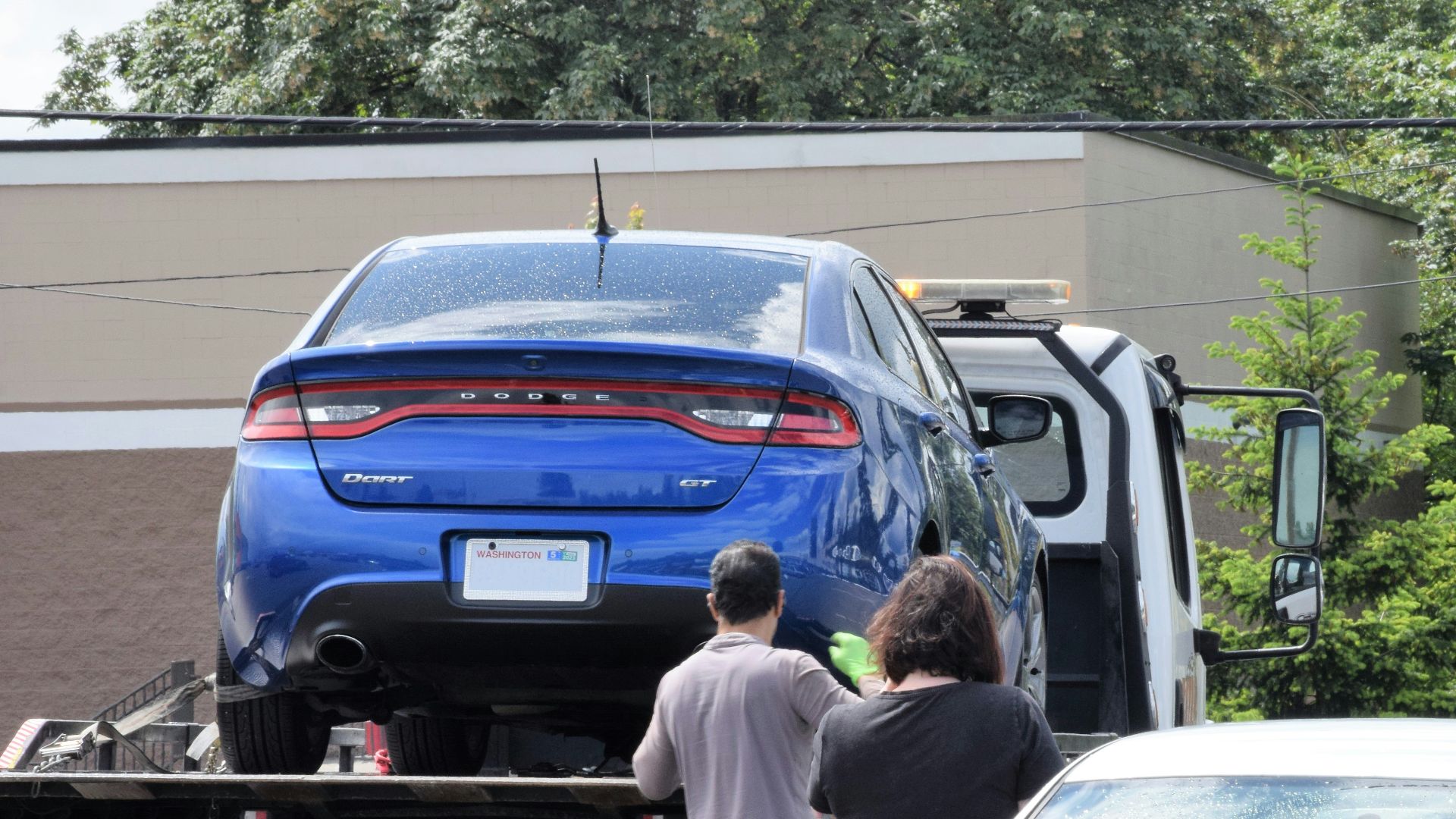 a blue car being loaded onto a flatbed truck